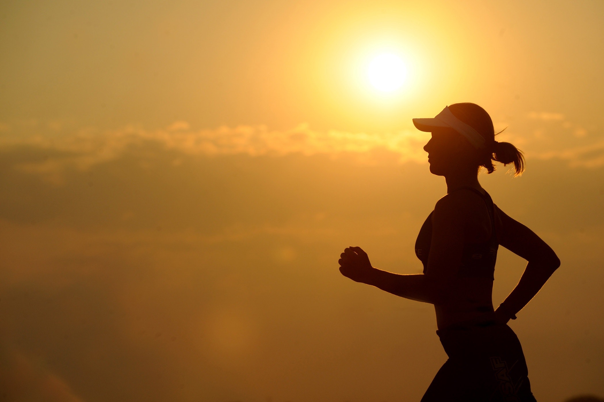 Kvinne jogger i solnedgang